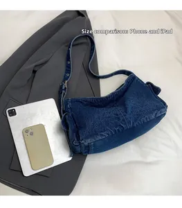 Detail view of denim crossbody bag size comparison with an iPad and smartphone