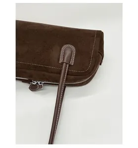 Close-up of dark brown suede Boston bag showing white stitching and durable texture