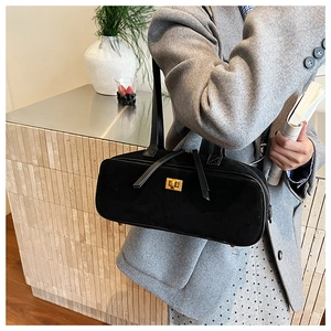 Close-up of minimalist black suede baguette bag with a premium golden twist lock closure