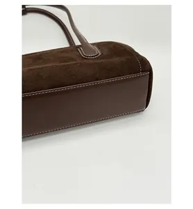 Detail of dark brown boston bag showing reinforced base and white contrast stitching