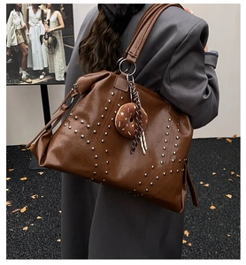 Detail of vintage brown tote bag with silver studs and a donut plush pendant charm