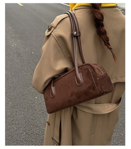 Detail of a brown suede Boston shoulder bag with white contrast stitching and long straps