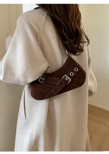 Detail view of brown suede underarm bag with vintage buckle and silver eyelet hardware
