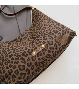 Detail der Canvas-Tragetasche mit Leopardenmuster, Lederriemen und modischem Logo-Patch