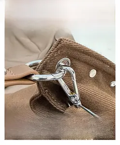 Detail of silver metal D-ring and swivel clasp on a brown canvas tote bag shoulder strap