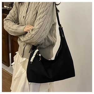 Détail du sac fourre-tout en daim noir avec breloque décorative en perles noir et blanc