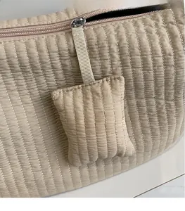 Dettaglio della borsa trapuntata beige con cuciture verticali e mini astuccio abbinato