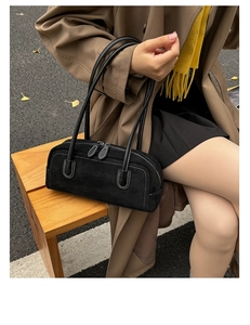 Detail of black suede Boston bag with white contrast stitching and dual zipper closure
