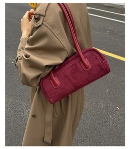 Detail view of burgundy suede Boston bag with white contrast stitching and long strap