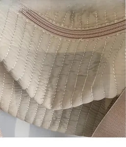Dettaglio della borsa trapuntata kaki con cuciture verticali e tracolla in nylon