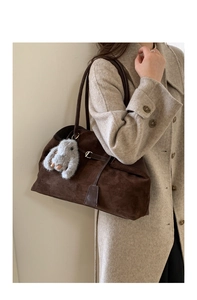 Detail of dark brown suede tote bag with plush rabbit charm and elegant metallic hardware