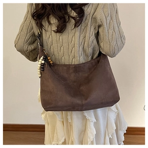 Détail du sac hobo en daim avec pendentif décoratif en perles de bois multicolores