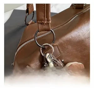 Detail of dark brown tote bag showing black metal ring hardware and plush donut charm