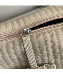 Dettaglio della borsa a tracolla trapuntata beige con zip argentata e tiralampo lungo