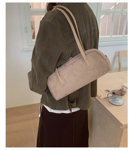 Detail of oat-colored suede baguette bag with silver zipper and slim shoulder strap