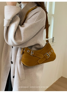 Detail showing mustard yellow suede motorcycle bag with metallic eyelets and buckle strap