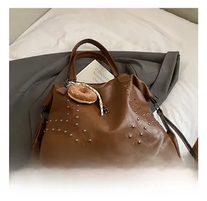 Detail of dark brown tote bag featuring silver metal rivets and a donut pendant