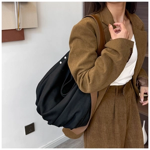 Detail showing high-capacity black canvas tote bag with ruched design and white metal studs