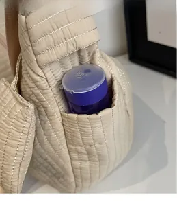 Dettaglio della tasca laterale e trama trapuntata della borsa hobo in colore beige