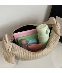 Interno spazioso della borsa a mezzaluna trapuntata beige con tablet e vari cosmetici