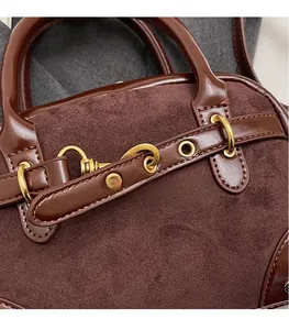 Detail of vintage brown suede handbag showing metal eyelets and gold hardware texture