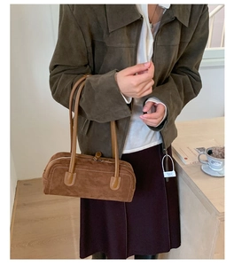 Close-up of vintage brown suede Boston bag with fine stitching and slim leather handles