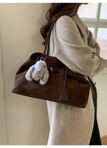 Detail of dark brown suede tote bag with grey rabbit fur charm on shoulder