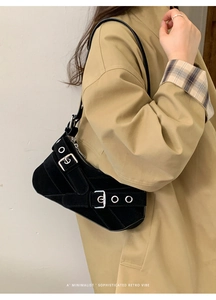 Detail of black suede hobo bag with silver metal buckles and eyelet straps in Y2K style