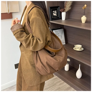 Detail of vintage brown canvas tote bag with wide strap and pleated design on shoulder
