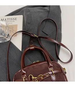 Detail view of coffee suede and leather patchwork bag with golden metal buckle and long strap