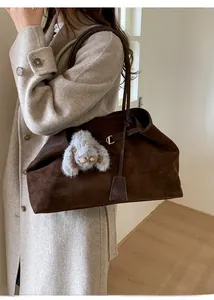 Detail view of large dark brown suede tote bag with shoulder strap and plush charm