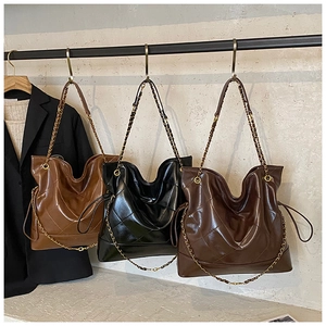Three oversized quilted tote bags in brown and black with chic metal chain straps