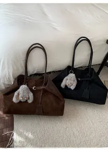 Detail of brown and black suede tote bags with silver buckles and plush rabbit charms