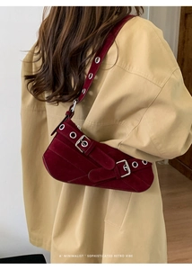 Detail shot of burgundy suede underarm bag with silver eyelets and buckle accents