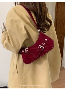 Detail of burgundy suede baguette bag with vintage buckles and metal eyelets on wide strap