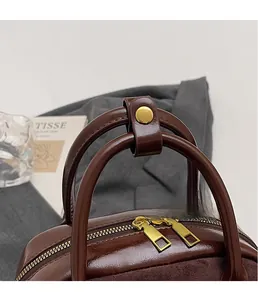 Detail of vintage brown oil wax leather bag with gold dual zippers and metal fasteners