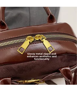 Close-up of smooth gold zipper hardware on a dark brown suede and leather handbag