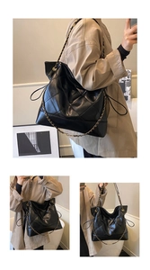 Detail view of black quilted tote bag with metal chain strap and drawstring design