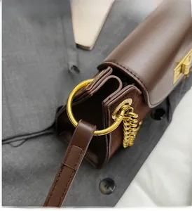 Detail der dunkelbraunen Lederhandtasche mit goldenem Metallring und strukturierten Beschlägen