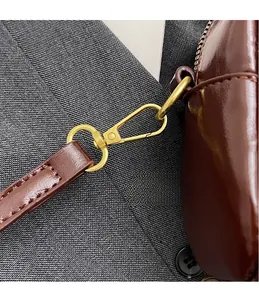 Detail of glossy dark brown faux suede bag featuring a premium polished gold metal hook