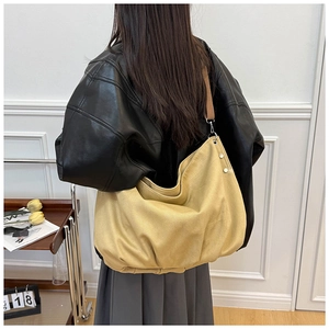 Detail of adjustable brown strap and soft pleated texture on yellow canvas tote bag