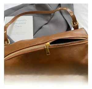 Close-up of vintage brown leather texture and premium gold zipper on cylindrical tote