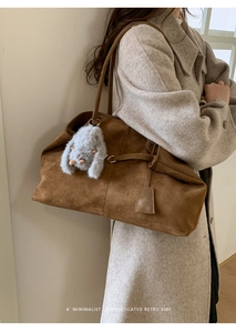 Brown suede tote bag detail with minimalist shoulder strap and plush bunny charm