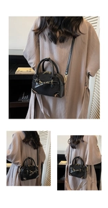 Detail of a vintage black Boston bag with metallic rivets and crossbody strap styling