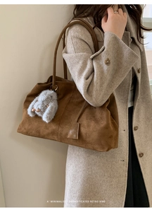 Detail of dark brown suede tote bag with a soft plush rabbit charm accessory