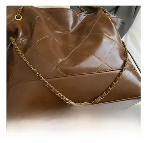 Close-up of golden metal chain and glossy diamond-quilted leather on a brown bag