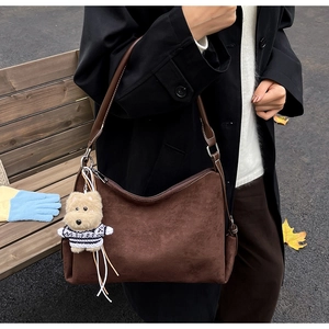 Detalle de bolso tote de ante marrón oscuro con un lindo colgante de perro de peluche