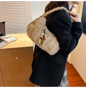 Detail of khaki plush handbag with braided shoulder strap and beaded charm on office desk