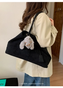 Black faux suede tote bag with plush rabbit pendant shown worn on the shoulder