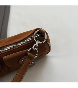 Detail von silbernem Metallreißverschluss und Kette an brauner Wildledertasche mit Gurt